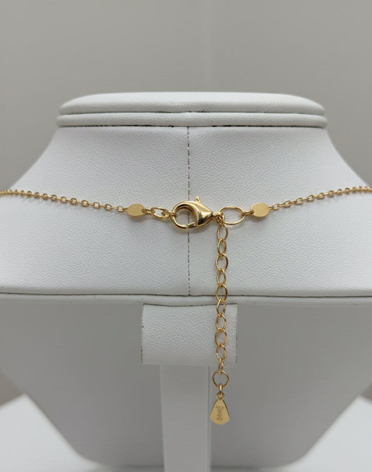 Gold necklace with a pendant on a mannequin bust against a gray background